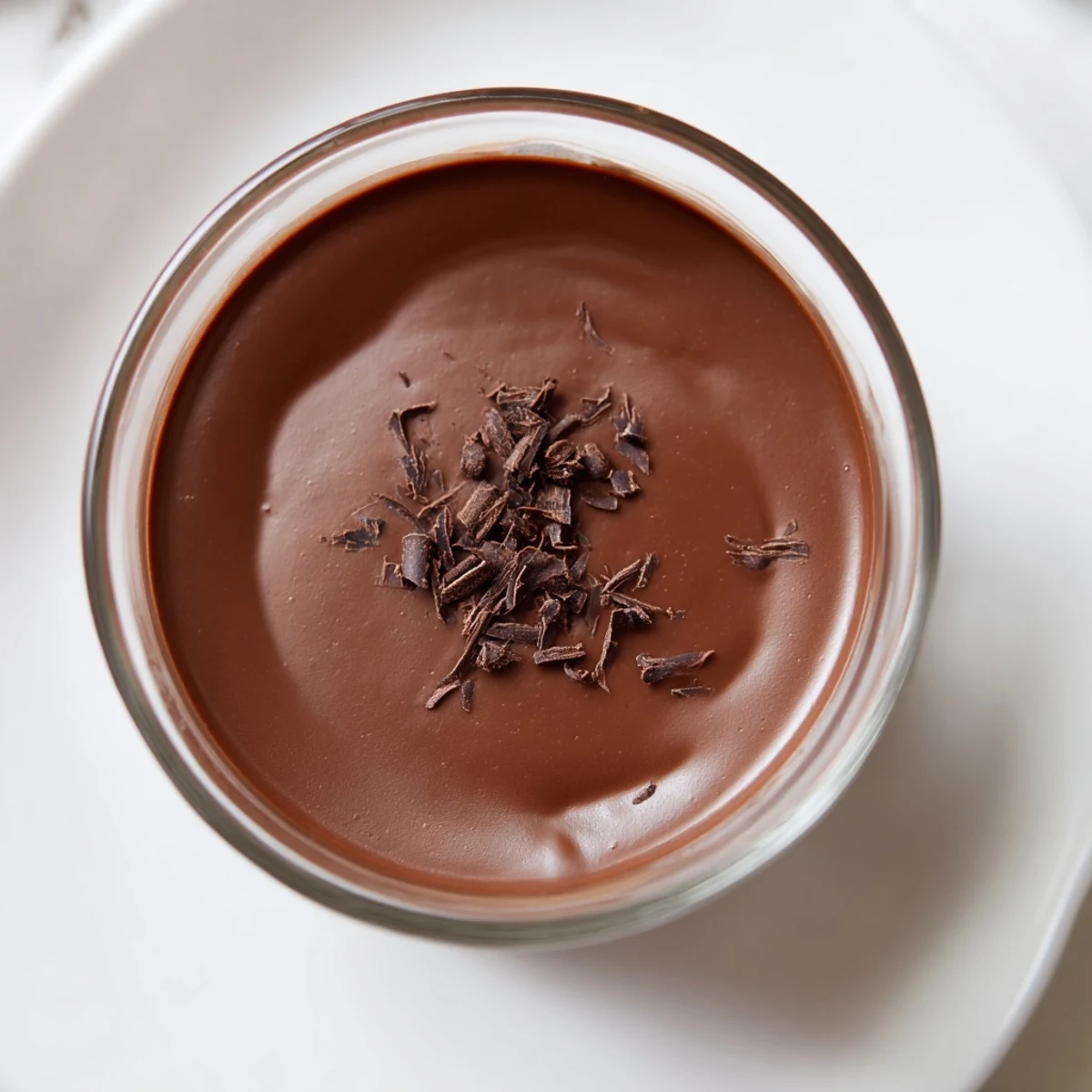 Homemade chocolate pudding, perfectly smooth and decadent, topped with a dollop of whipped cream.