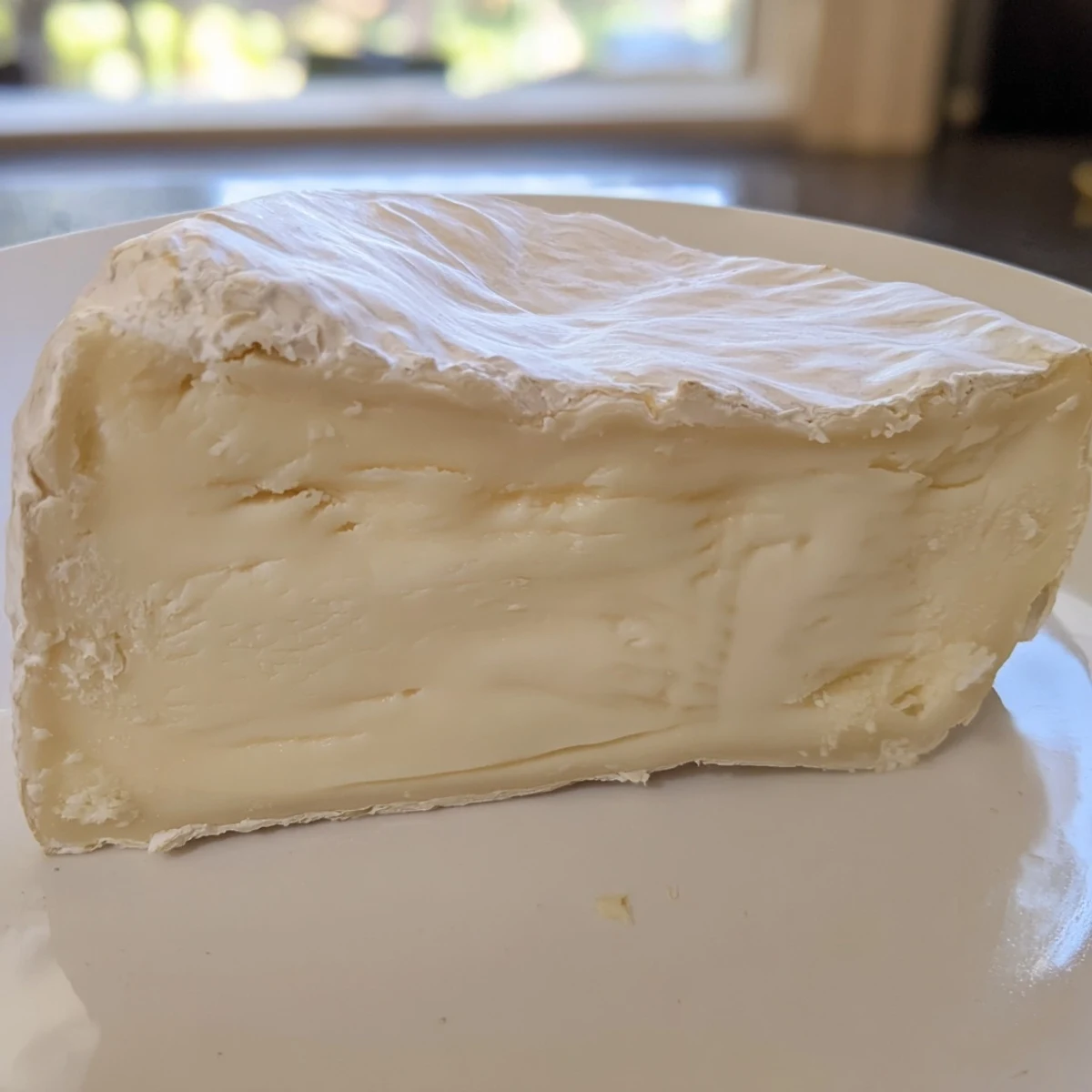 Close up shot of creamy Brie cheese on a cheese board, inviting you to enjoy its rich flavor.