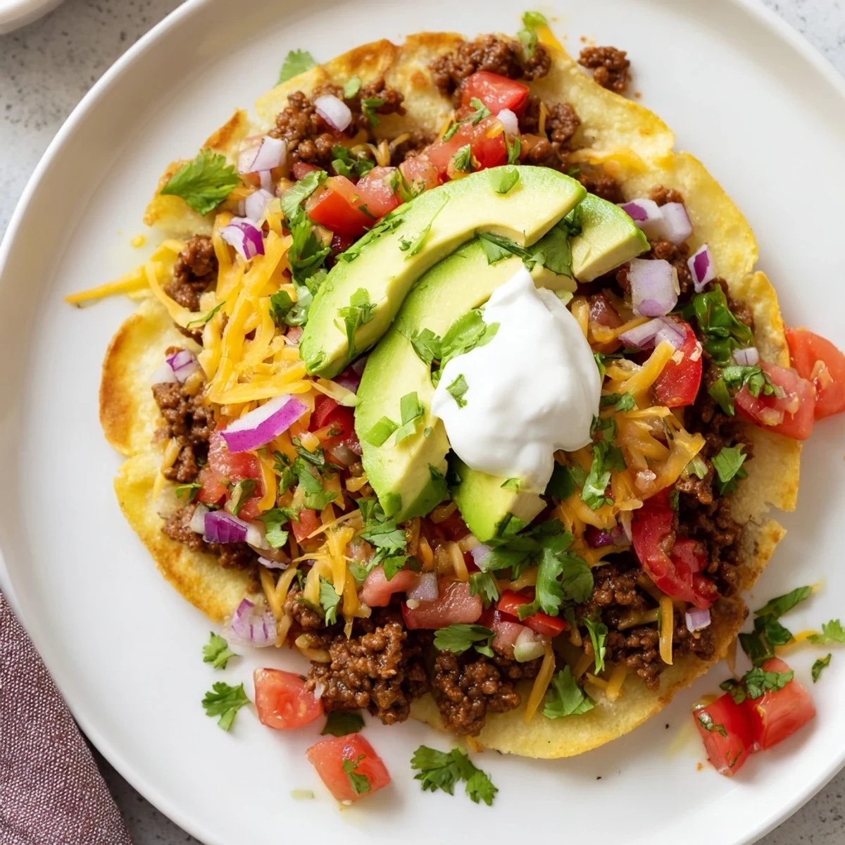 Close-up of crispy beef tostadas showcasing seasoned ground beef, fresh salsa, and golden cheese.