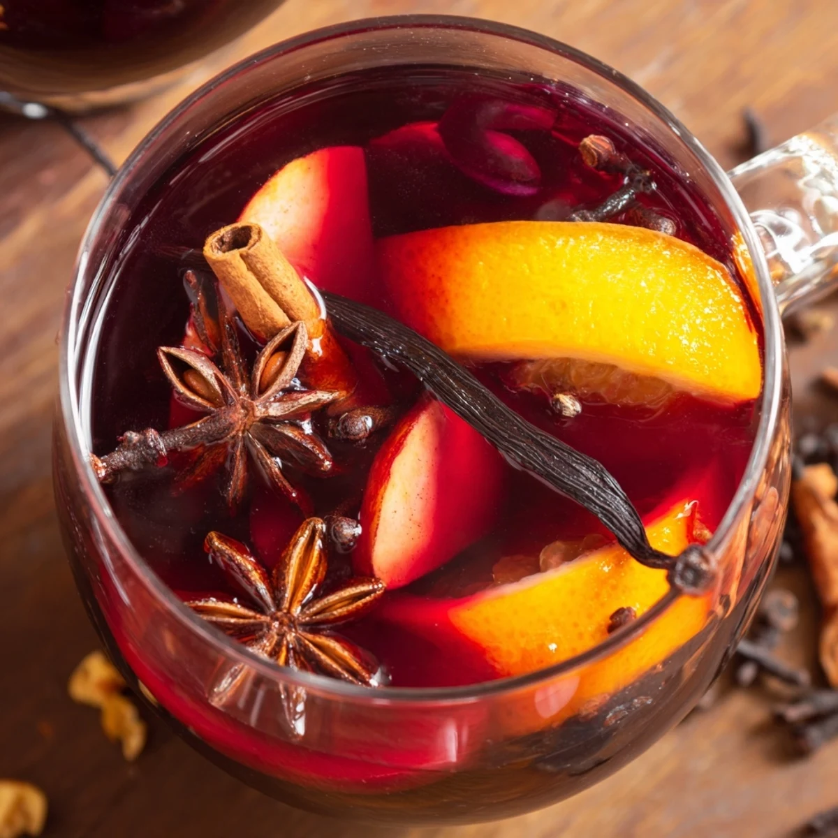 Vin épicé sans alcool fumant dans des mugs, avec orange et clous de girofle.