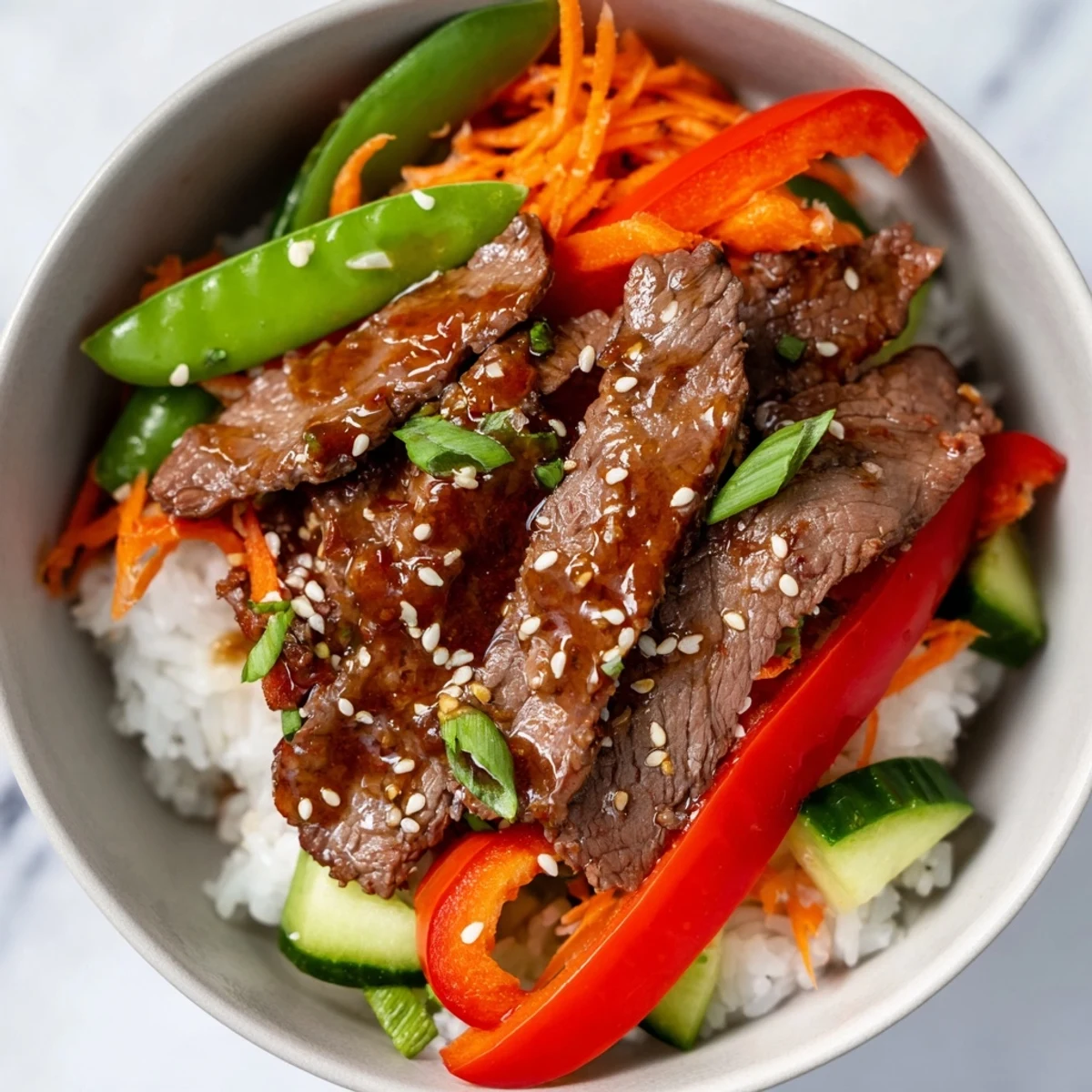 Bol de bœuf tendre sur riz vapeur, concombre frais et sauce umami.