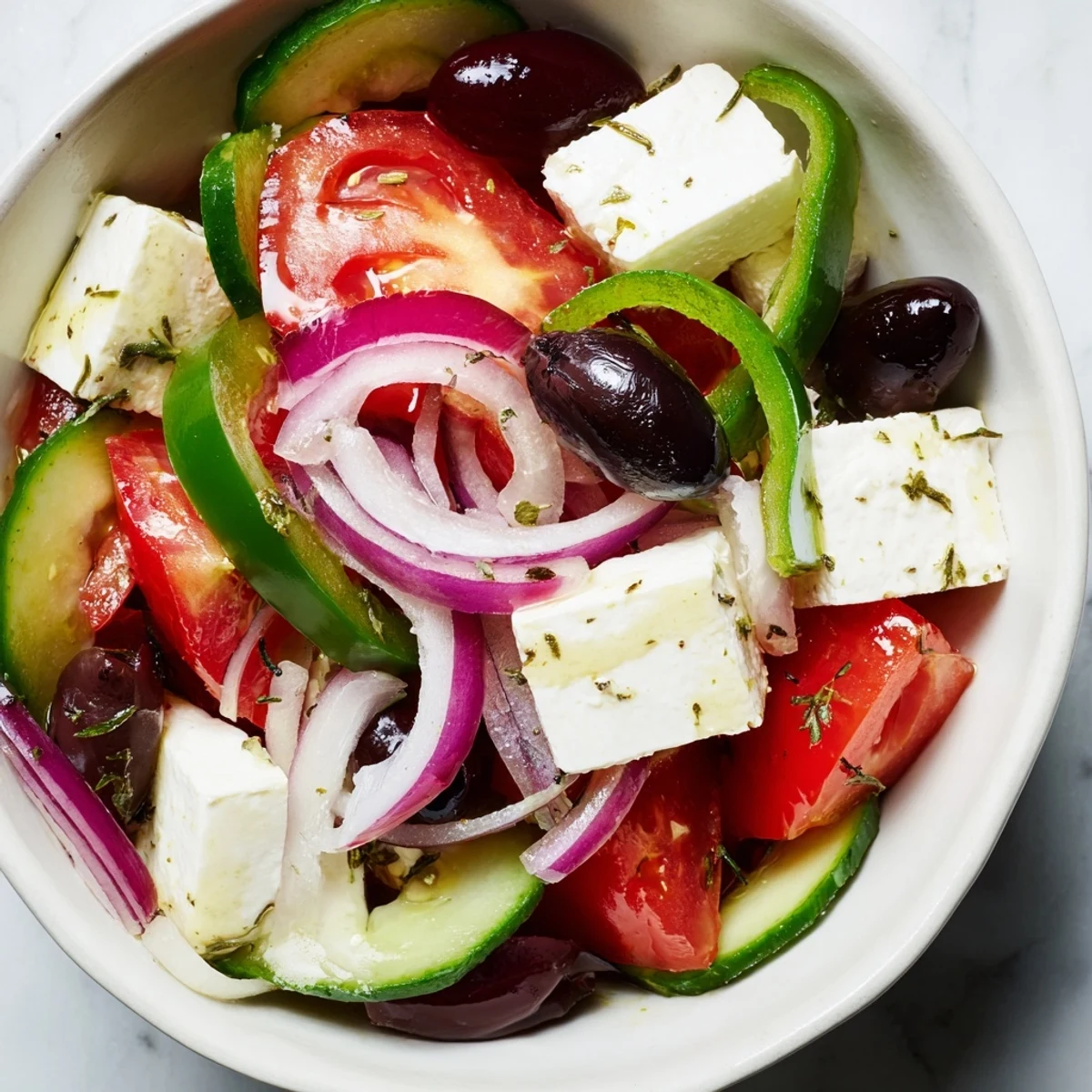 Salade grecque avec olives Kalamata et feta présentée sur un plat en céramique, garnie d'herbes fraîches.