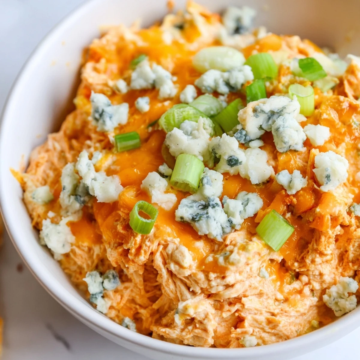 Gooey Spicy Buffalo Chicken Dip with Celery and Chips in a skillet, garnished with green onions and ready for scooping.