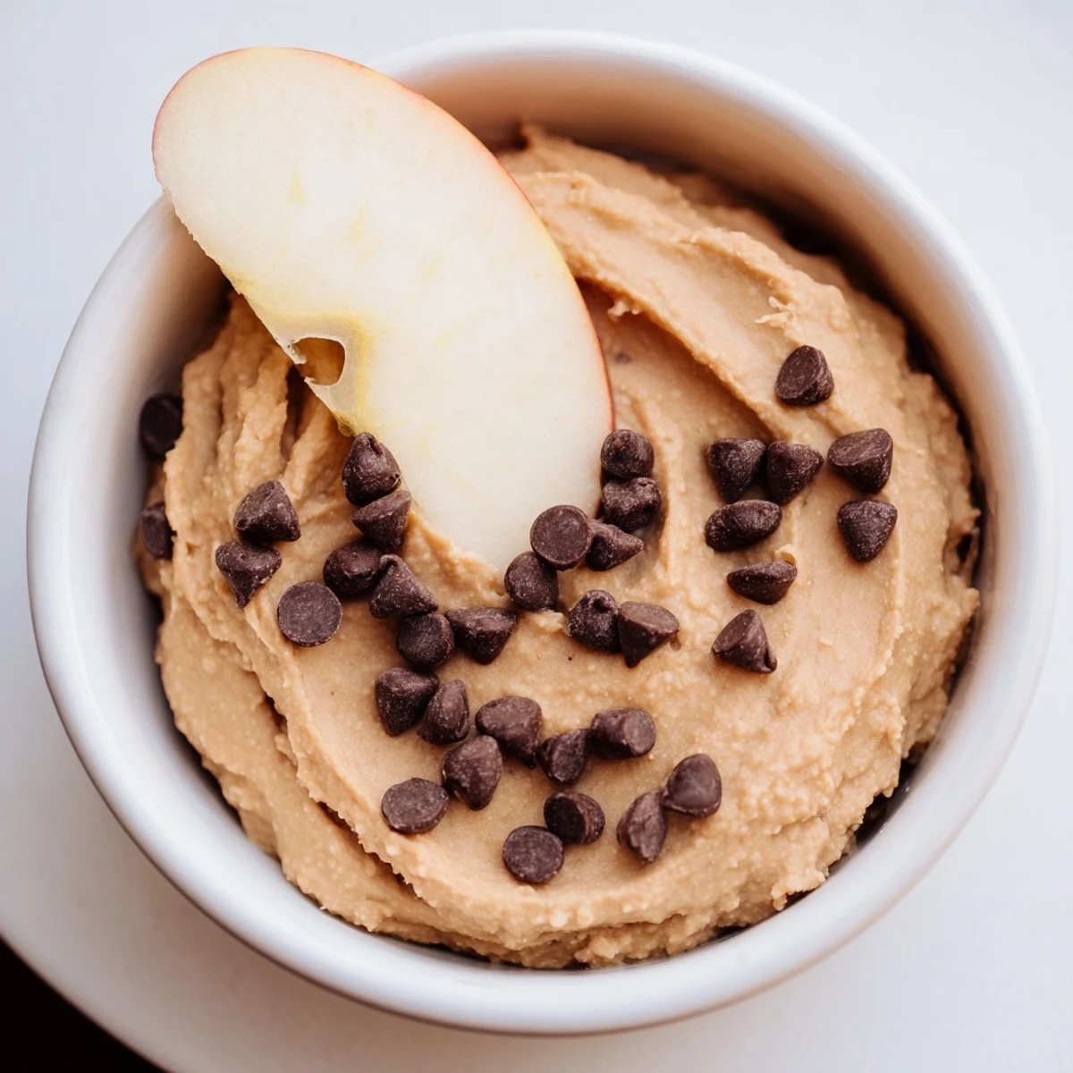 Bol de Chocolate Chip Cookie Dough Hummus avec des rondelles de pommes croquantes et de copeaux de chocolat