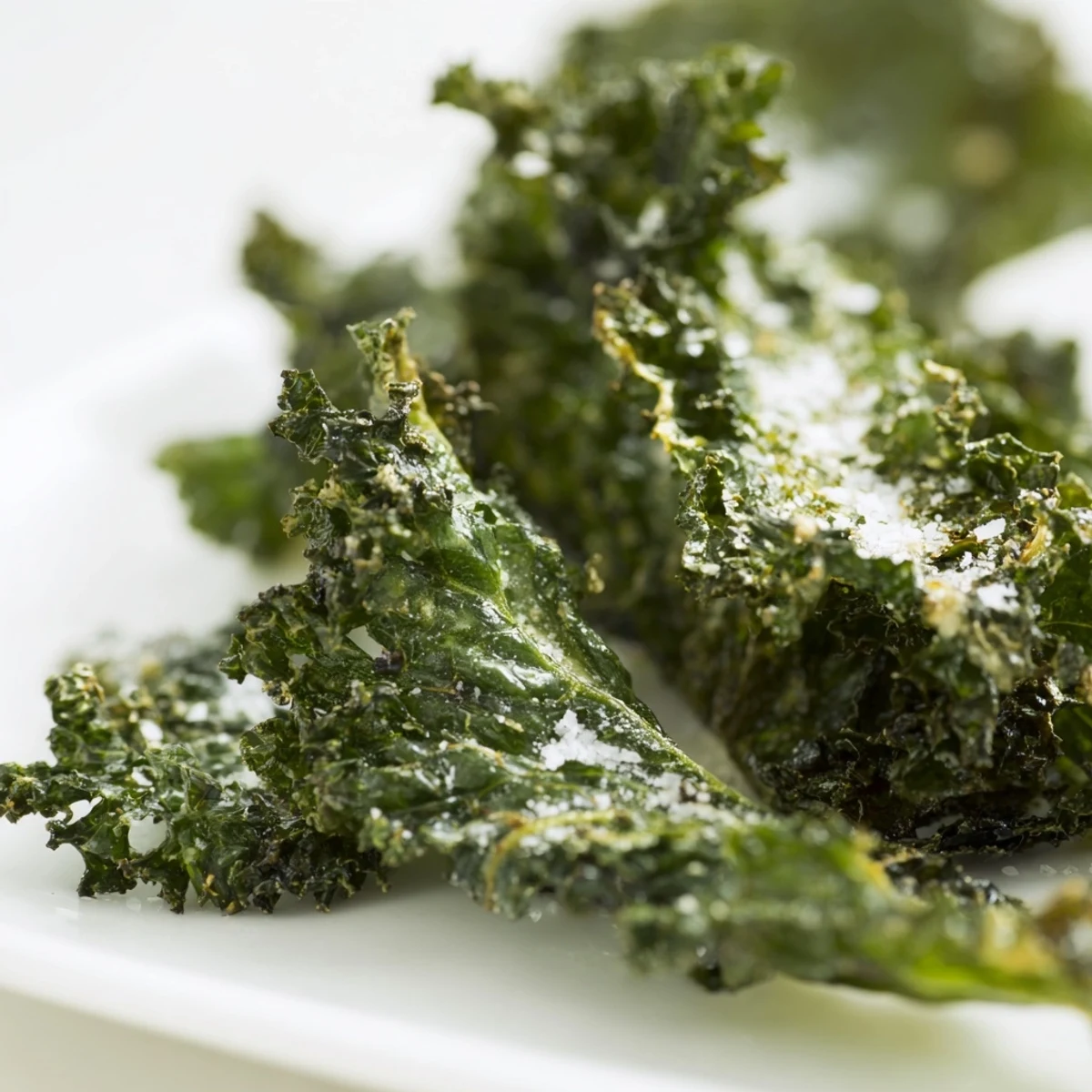 Croustillants kale chips au four assaisonnés au sel de mer, parsemés de flocons brillants pour un snack croustillant et savoureux.