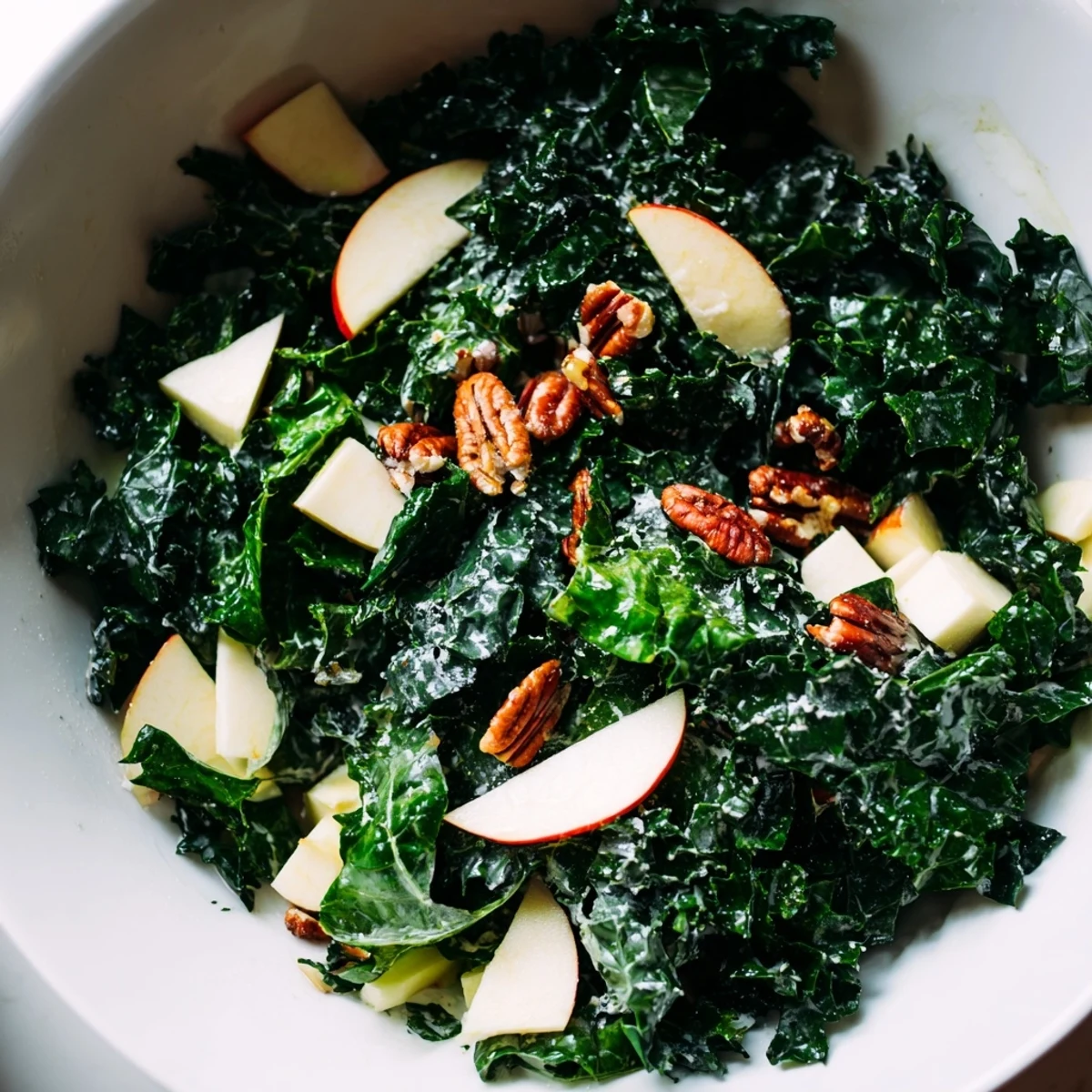 A hearty bowl of Winter Kale Salad with Apple and Cheddar, tossed in a light apple cider and maple dressing, perfect for a healthy vegetarian lunch.