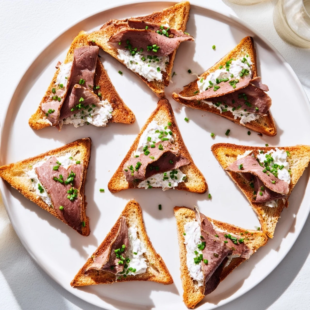 Coupes de pain dorées garnies de fines tranches de bœuf, sauce onctueuse et ciboulette, parfaites pour apéritif élégant