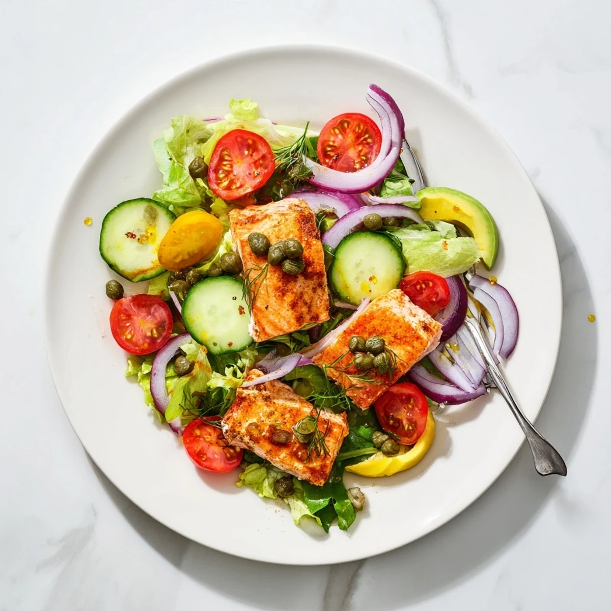 Salade au Saumon Cuit au Four présentée avec des tomates cerises, des tranches d'avocat et une vinaigrette citronnée.