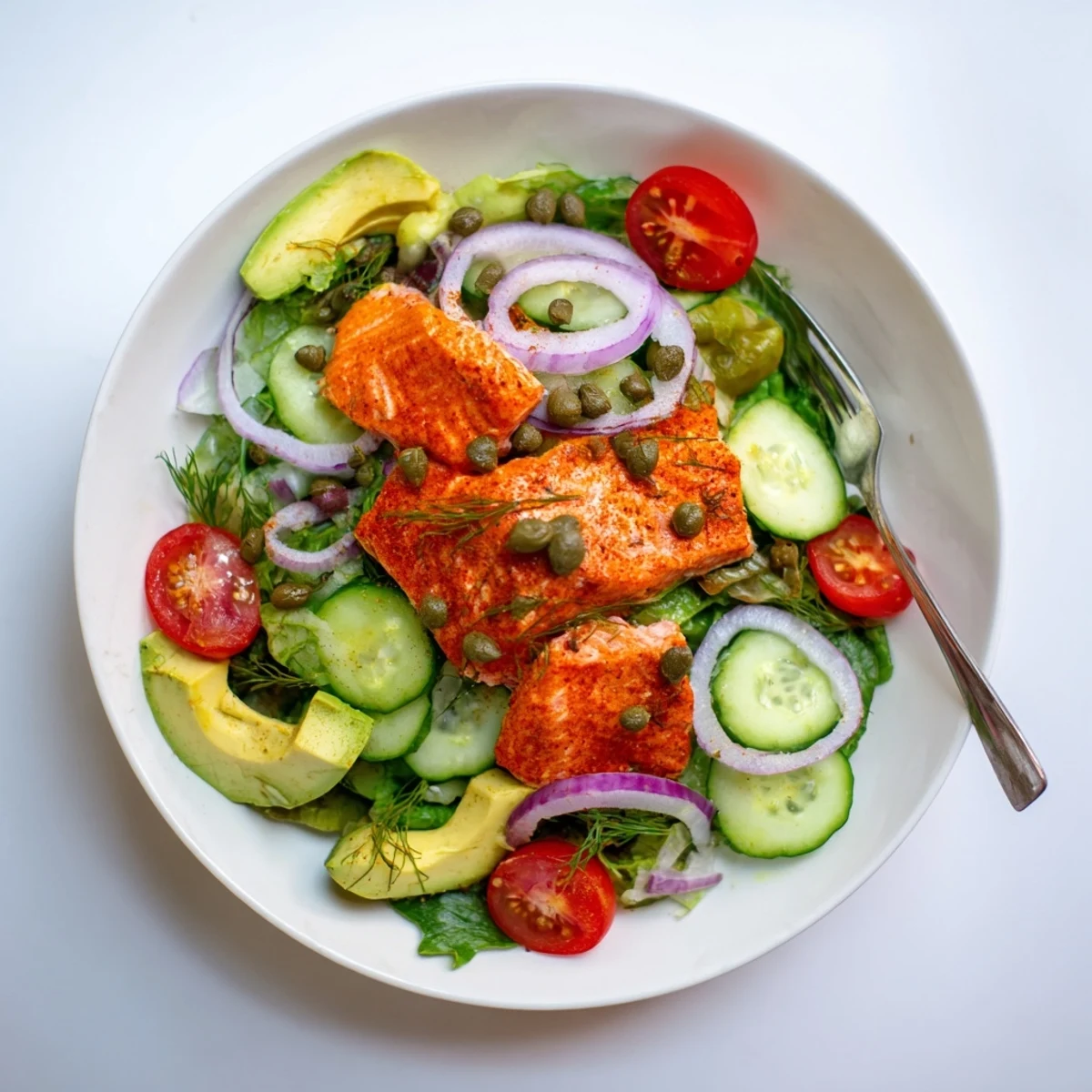 Saumon Cuit au Four encore tiède, émietté sur une salade verte avec des cornichons et oignons rouges.