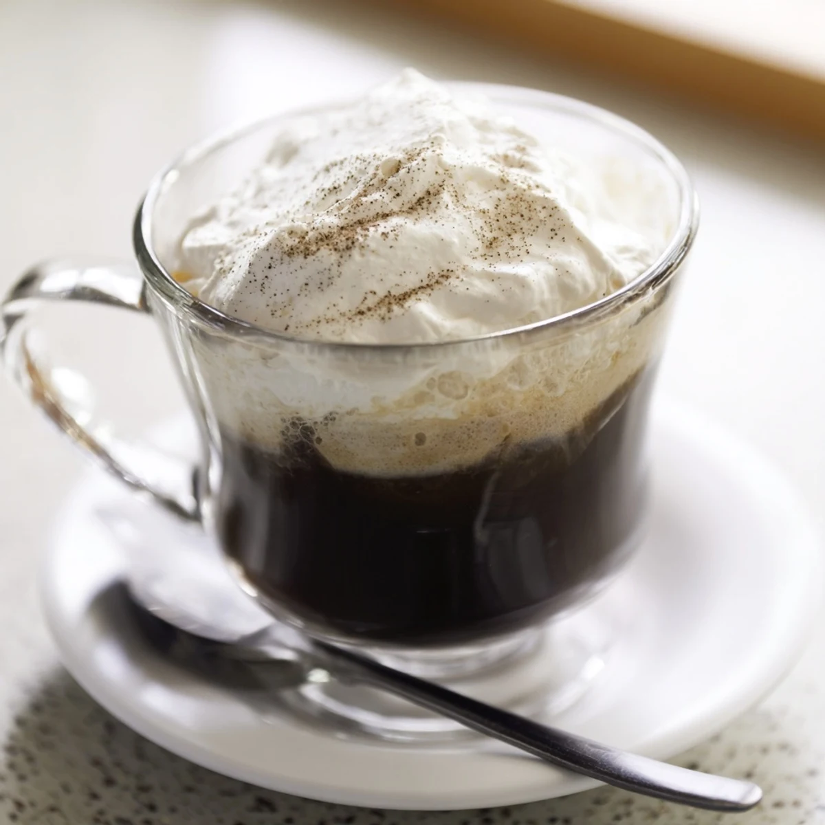 Irish Coffee Mocktail with Whipped Cream topped with nutmeg and a spoon nearby, ready to serve.