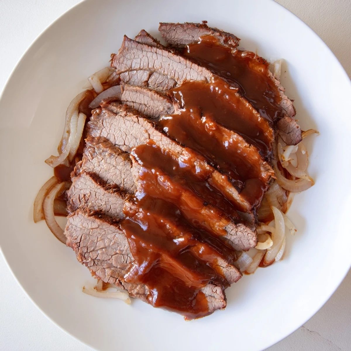 Slow cooked beef brisket with BBQ sauce glistening in a slow cooker, topped with homemade smoky barbecue sauce for a hearty American dinner.