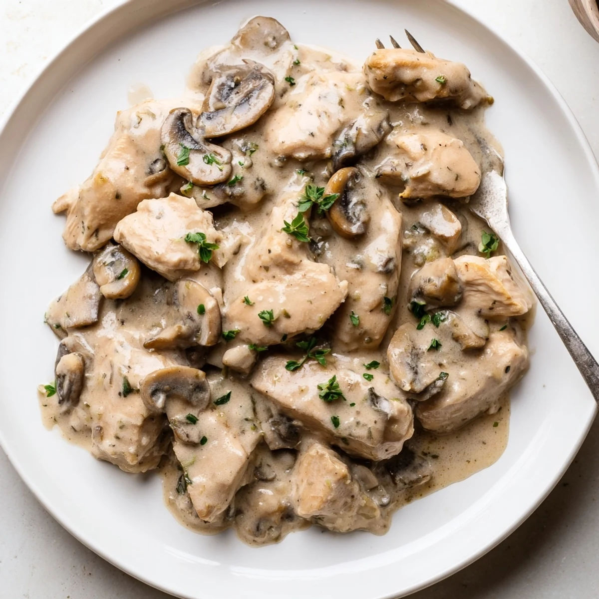 Une image savoureuse du plat principal "Creamy Mushroom Chicken Skillet" présenté dans une poêle en fonte, avec des morceaux de poulet dorés nappés d'une sauce crémeuse aux champignons.