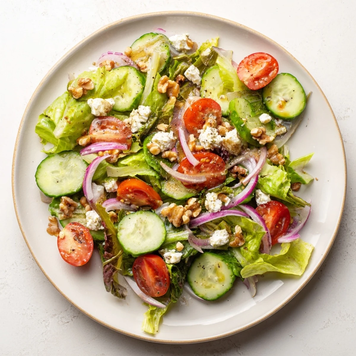 A close-up of Spring Mix Salad with Vinaigrette in a white bowl, showcasing fresh lettuce, walnuts, and a light balsamic dressing for serving.