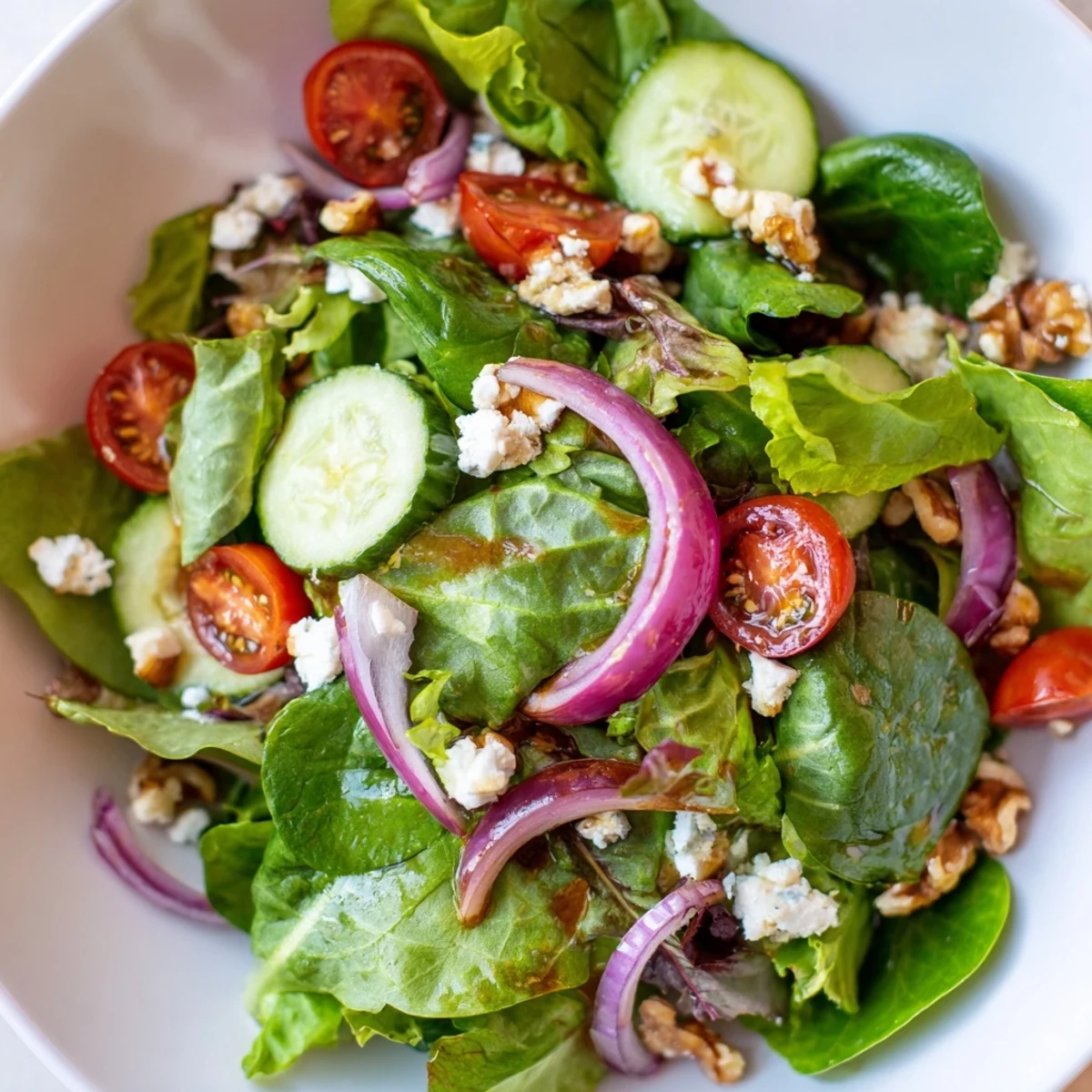 Salade printanière avec vinaigrette balsamique, un bol vibrant de légumes croquants et de fromage feta surmonté de noix toastées.