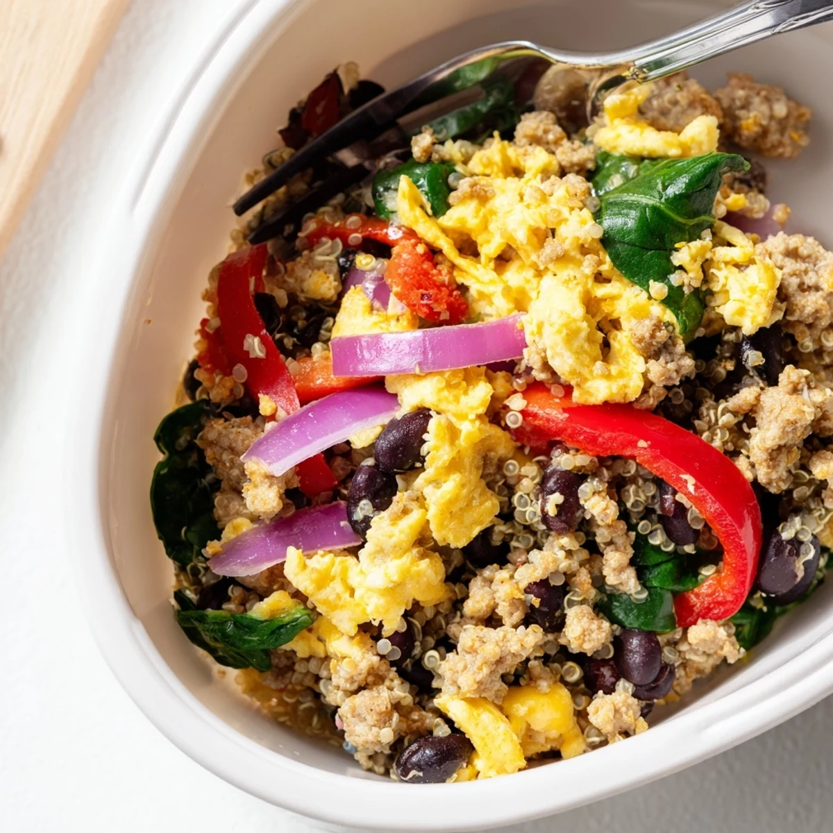 Hearty high protein freezer friendly breakfast bowls with scrambled eggs, quinoa, and colorful vegetables in meal prep containers