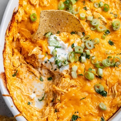 Spicy Buffalo Chicken Dip crémeux et épicé, présenté dans un plat à gratin avec un pile de tortilla chips croustillantes.