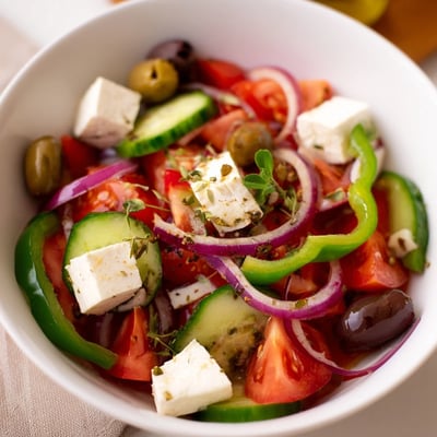 Bol de salade grecque aux olives Kalamata et feta, avec tomates rouges et concombre croquant bien assaisonnée.