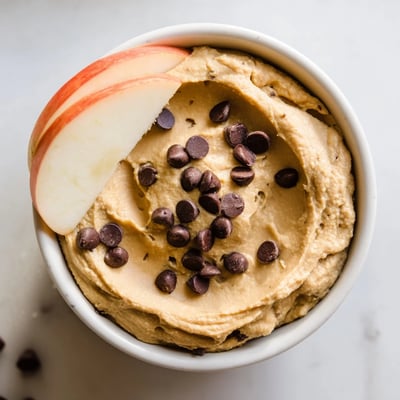 Cette délicieuse trempette à la pois chiche édulcorée au sirop d'érable est garnie de copeaux de chocolat et servie avec des tranches de pommes croquantes