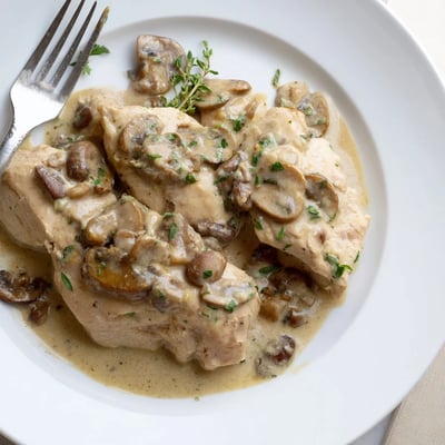 Le plat fini "Creamy Mushroom Chicken Skillet" fume doucement, révélant une sauce onctueuse aux aiguilles de thym et des champignons brunis parfumés à l'ail.