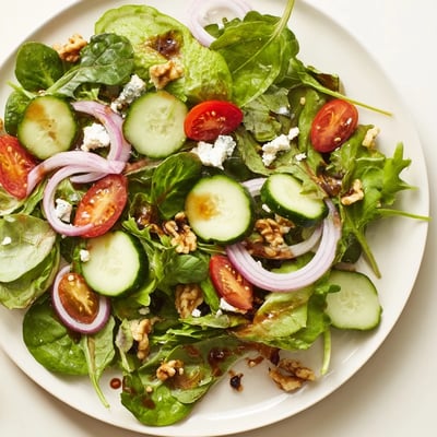 Spring Mix Salad with Balsamic Vinaigrette présentée sur une nappe claire, feuilles tendres et tomates cerises éclatantes pour un déjeuner léger.