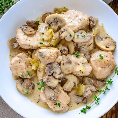 Assiette de Creamy Mushroom Chicken Skillet garnie de champignons dorés et de thym frais.