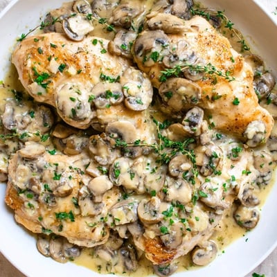 Tender chicken breasts in the Creamy Mushroom Chicken Skillet served beside fluffy mashed potatoes and fresh parsley