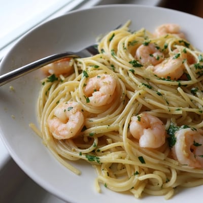 Crevettes roses sautées dans l'ail et le persil sur assiette de spaghetti scampi au fromage Parmesan